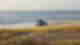 Car driving along the ocean by the waves on clear stretches of golden sand, near some grasslands, Australia