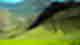Bright green valley with terraced ruin hills surrounded by green mountaisn and a little village at the bottom with blue skies