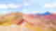 Candy coloured striped rainbow mountains on a sunny day with some white clouds