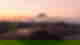 Crater volcanoes and more volcanoes in the distance with a veil of mist under baby pink skies at sunrise